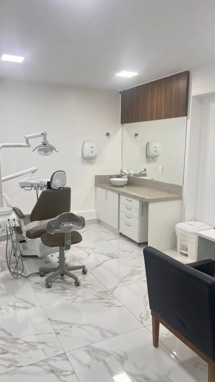 Consultório odontológico com cadeira, bancada e pia
