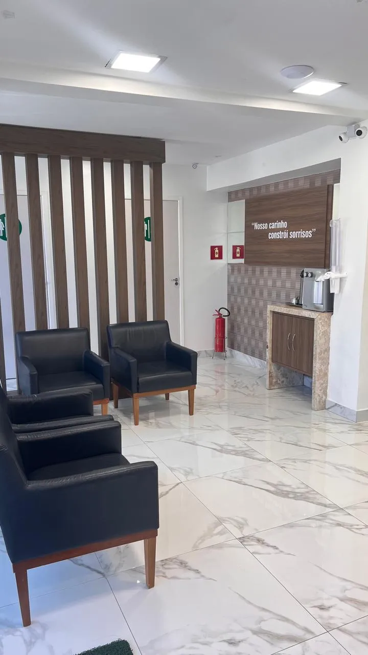 Sala de espera da clínica, com poltronas e piso claro